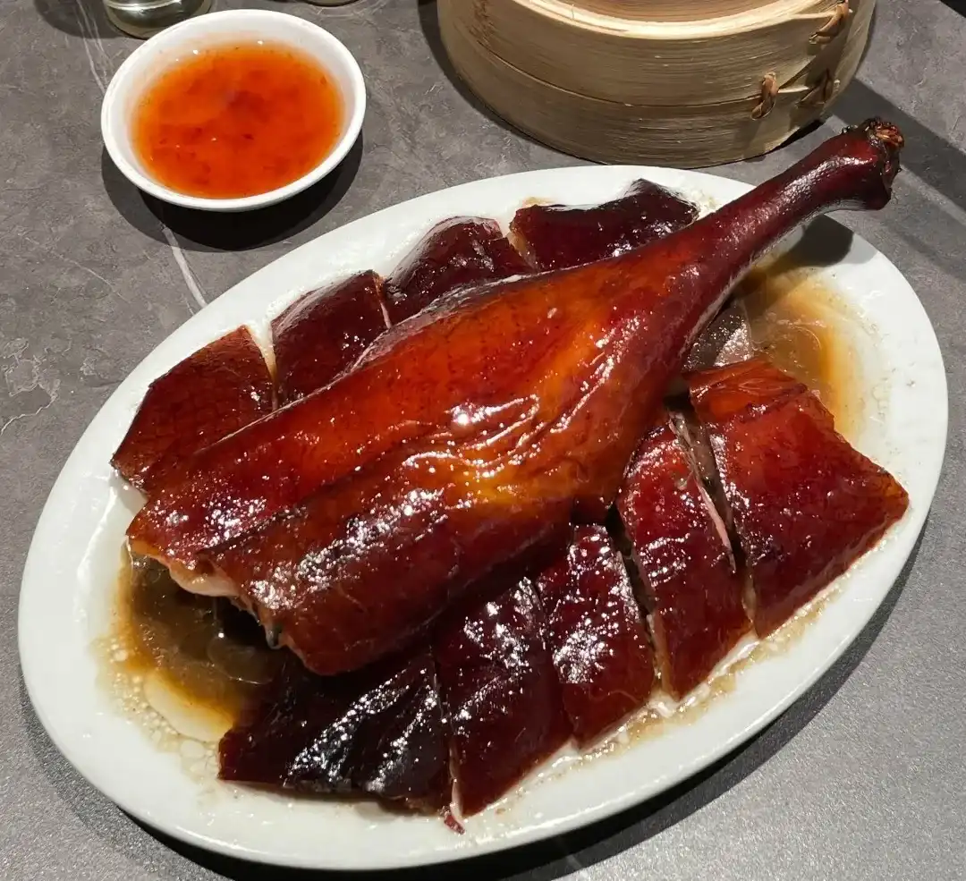 Bone-in pieces of Gongming roast goose arranged with a whole leg on a white plate
