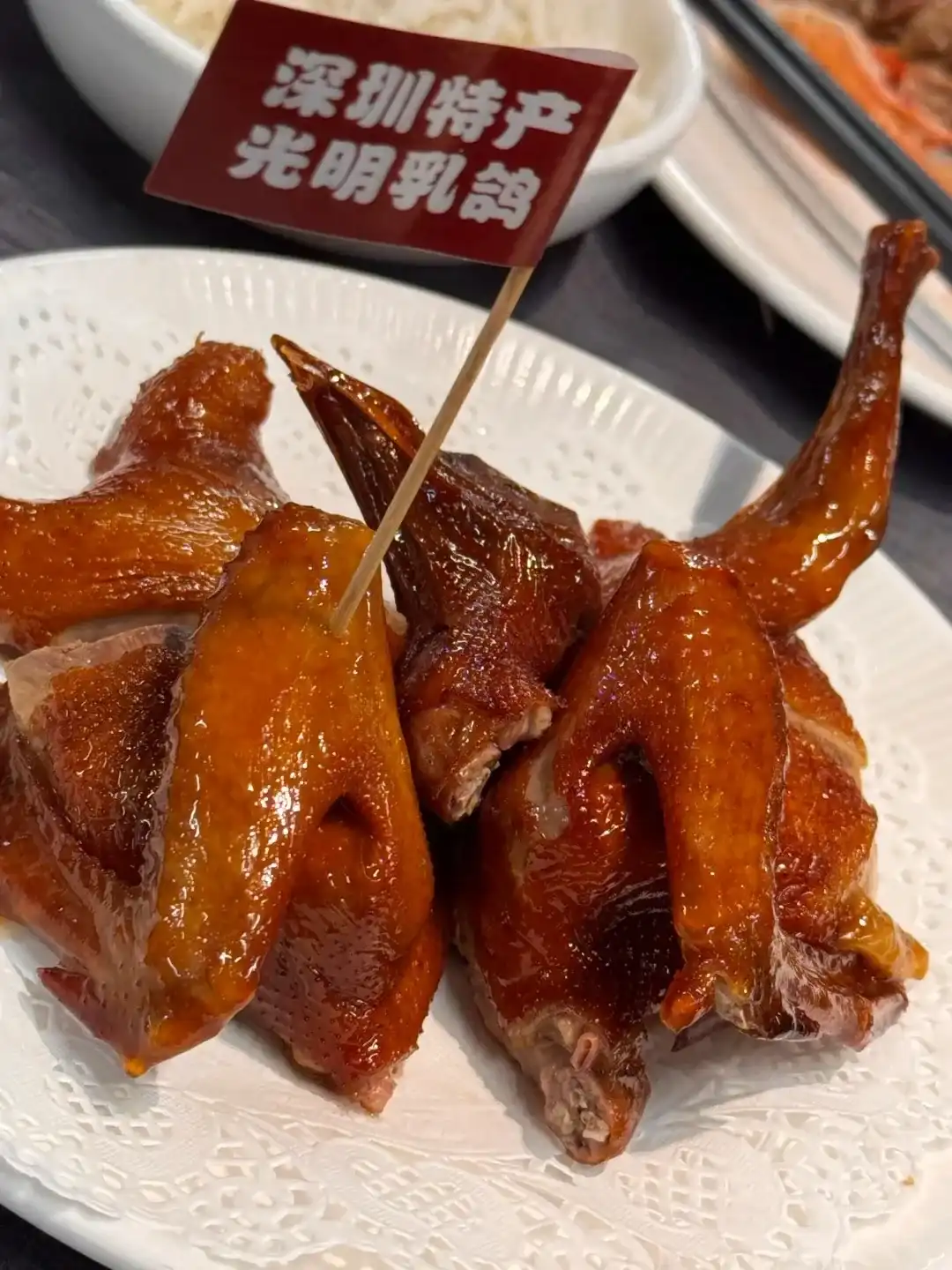 Glossy brown-red pieces of Guangming squab arranged on a white plate