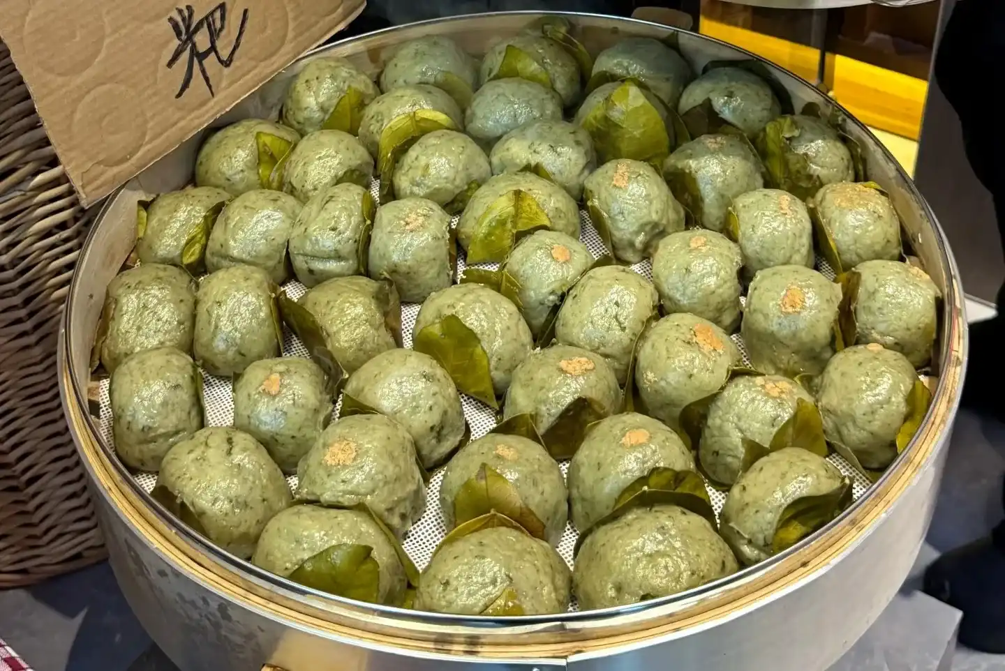 Round green haozi baba rice cakes arranged in a bamboo steamer