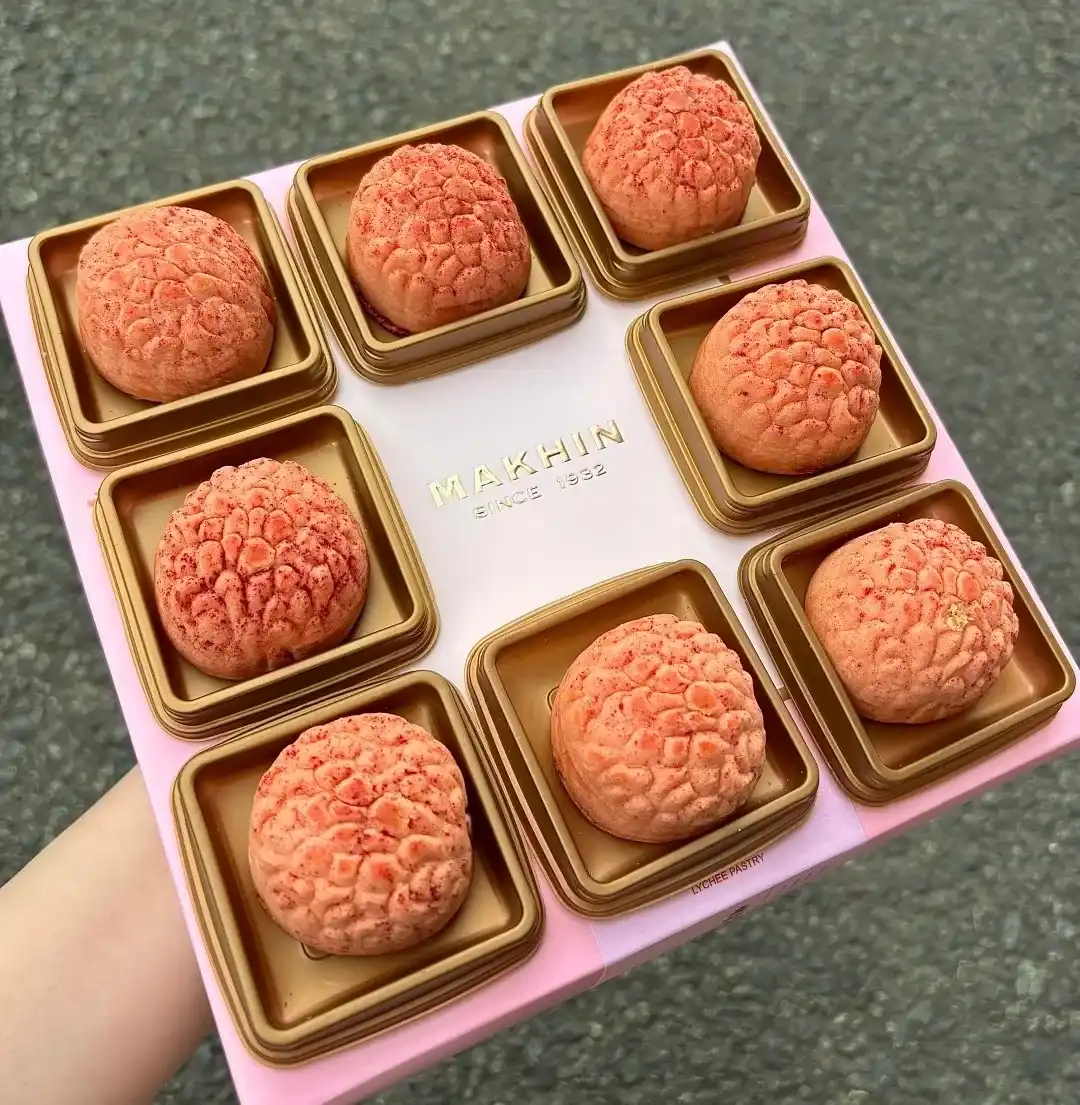Pink lychee-shaped pastries displayed beside individual wrappers