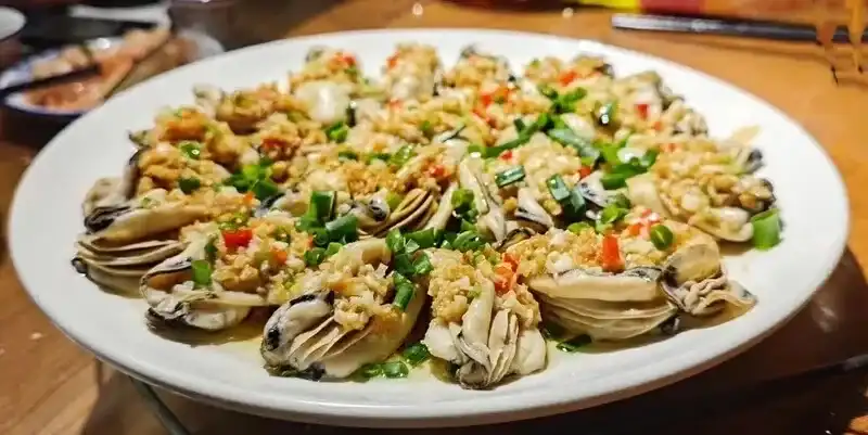 Cooked oysters on the half shell topped with garlic, red chilli and scallions
