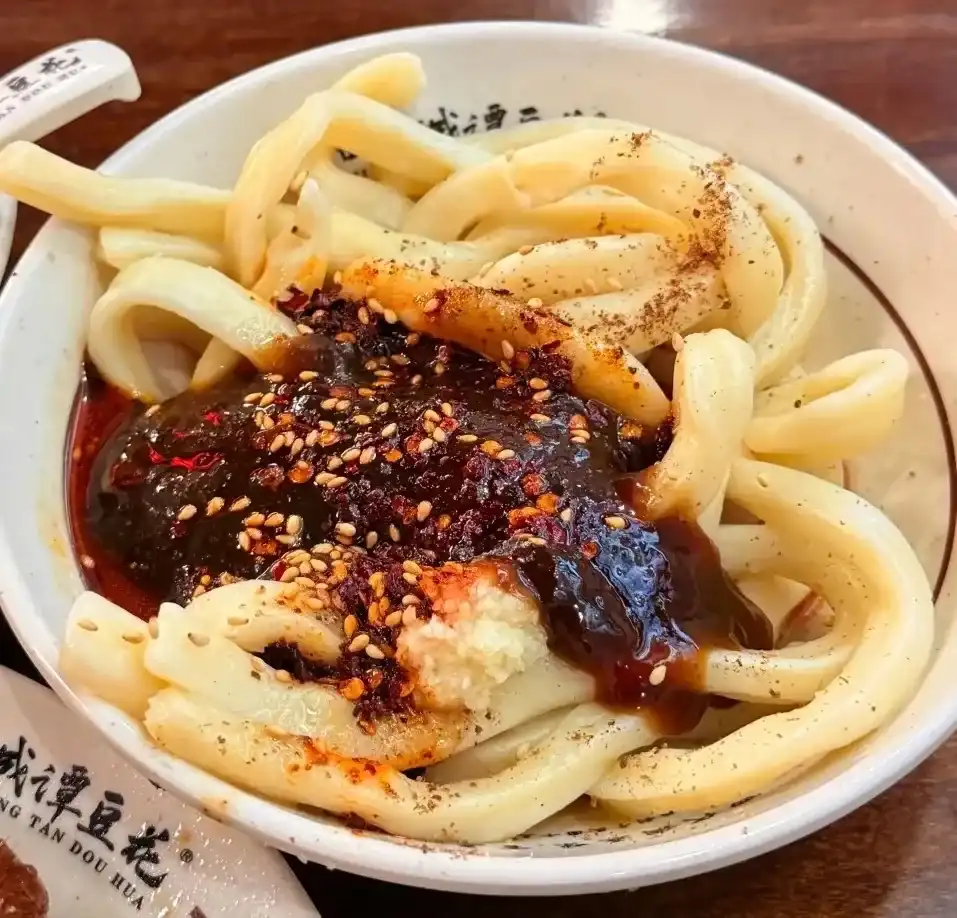 Thick sweet-water noodles mixed with chilli oil, aromatic soy, garlic, and peanuts