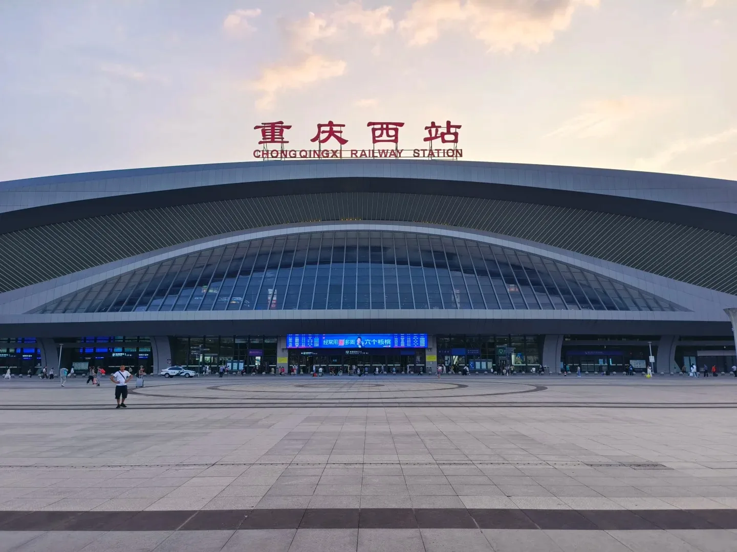 Curved Chongqing West Railway Station building and approach roads at dusk