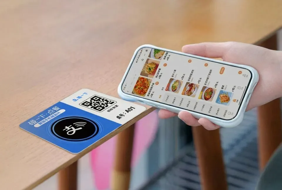 Phone touching an official Alipay NFC table marker and opening a restaurant Mini Program