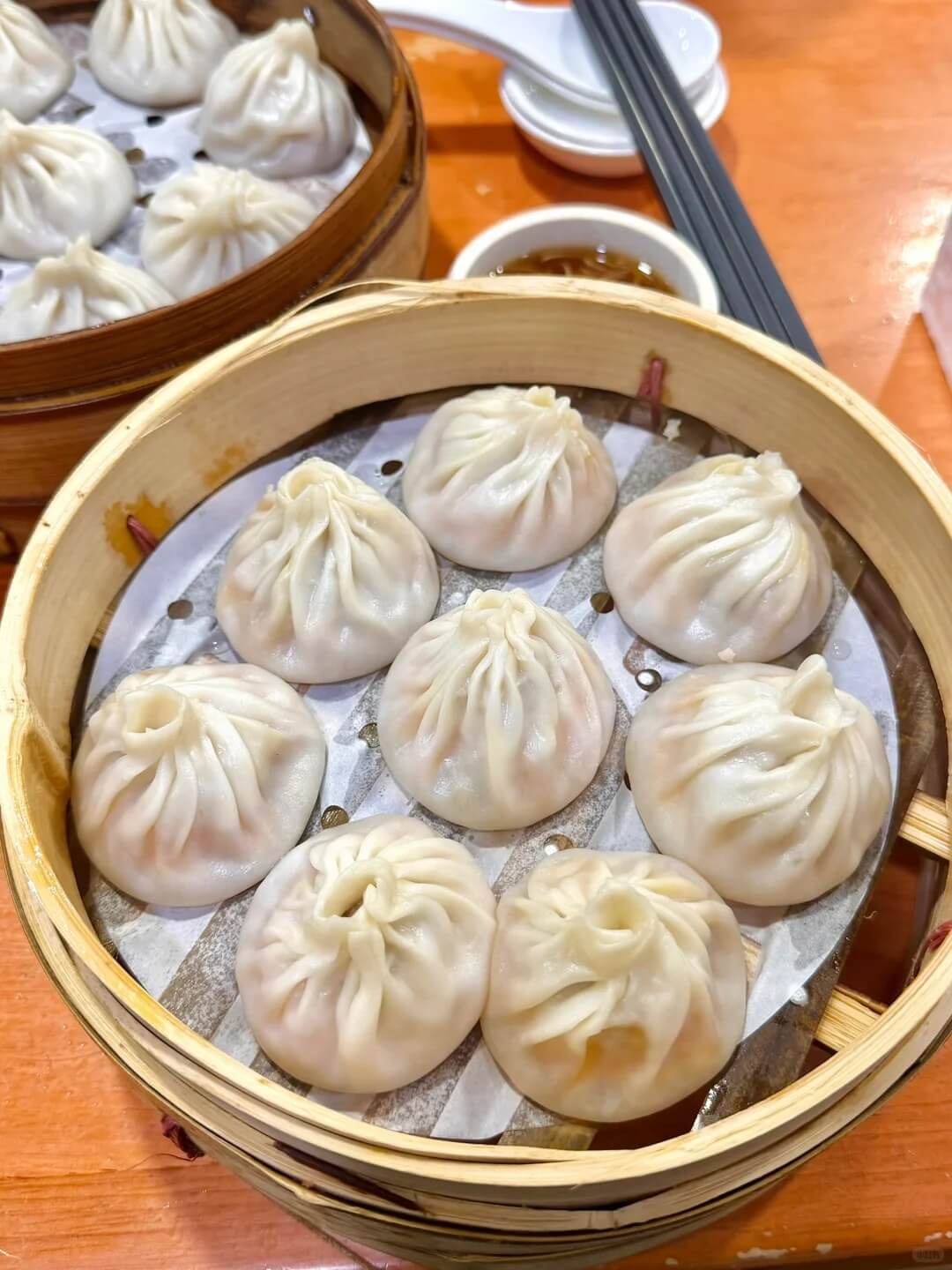 Two bamboo steamers of Shanghai xiaolongbao filled with pork and hot soup