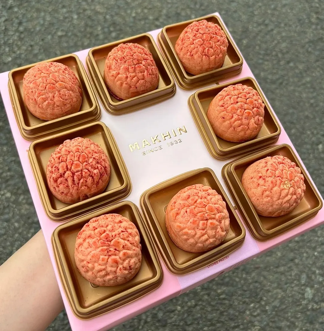 Pink lychee-shaped pastries displayed beside individual wrappers
