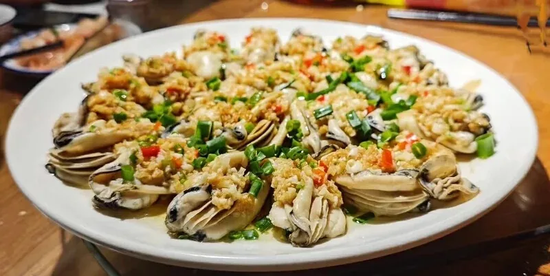 Cooked oysters on the half shell topped with garlic, red chilli and scallions